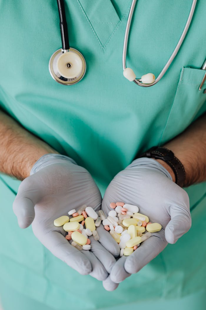 Medical professional in scrubs holds various pills, symbolizing healthcare and medicine.